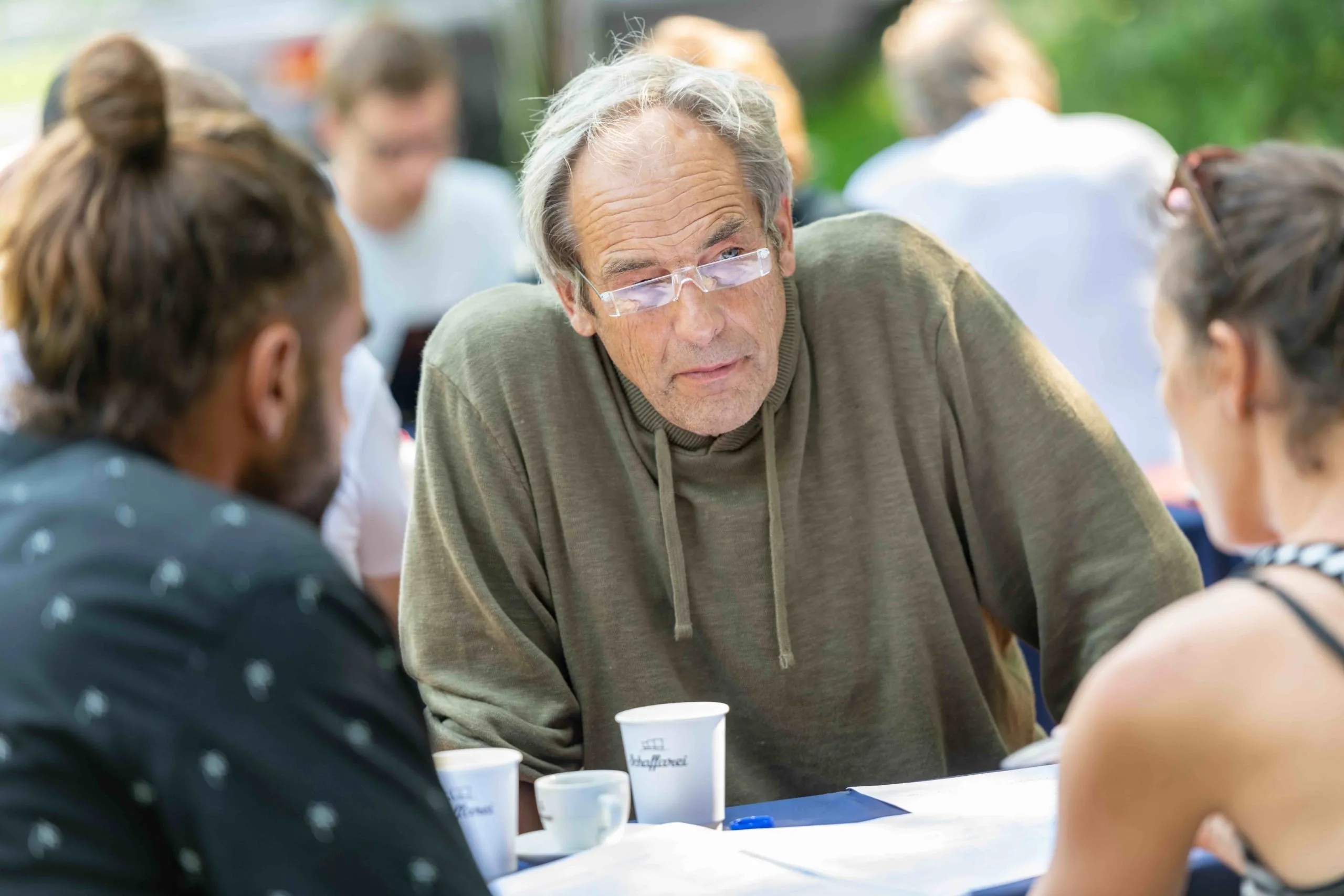 Nachdenklicher Mann mit durchsichtiger Brille und grünem Pullover