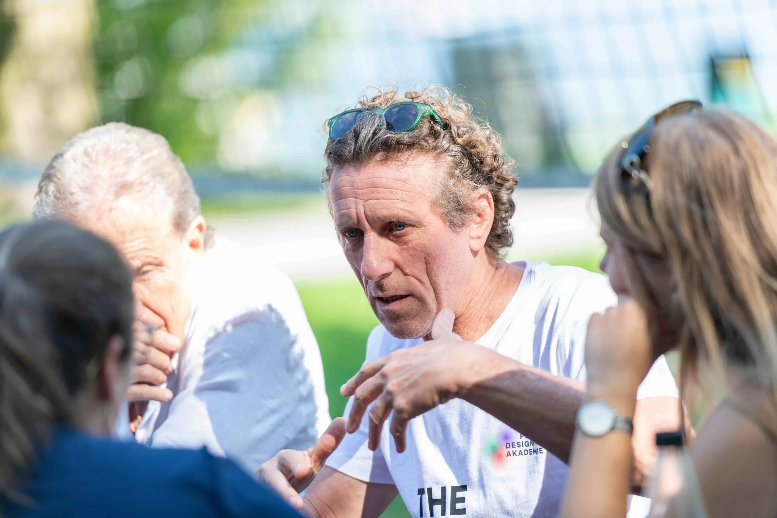 Diskutierender Mann mit Sonnenbrille auf dem Kopf und weißem T-Shirt