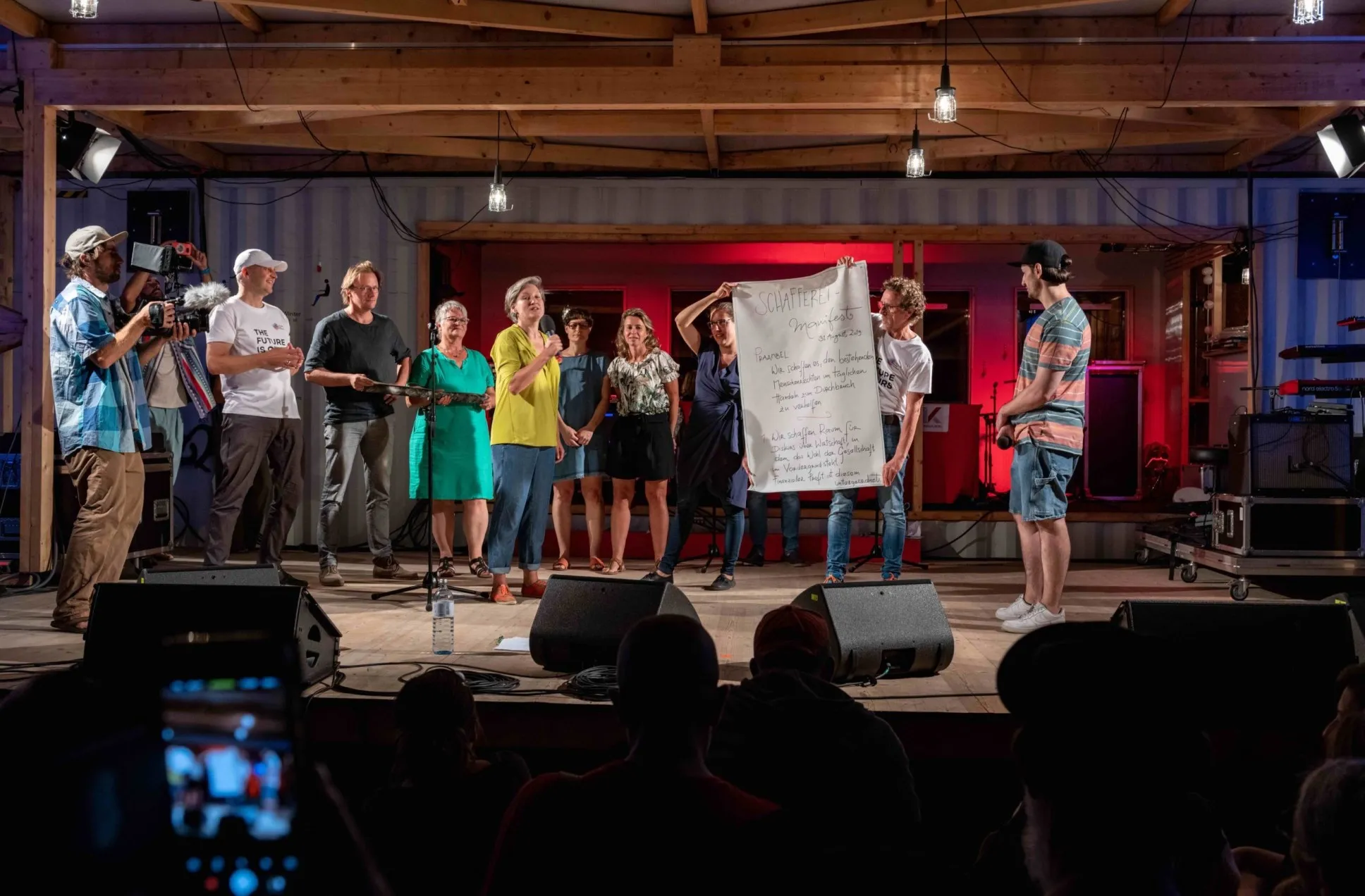 Menschen präsentieren ein Plakat auf einer Bühne