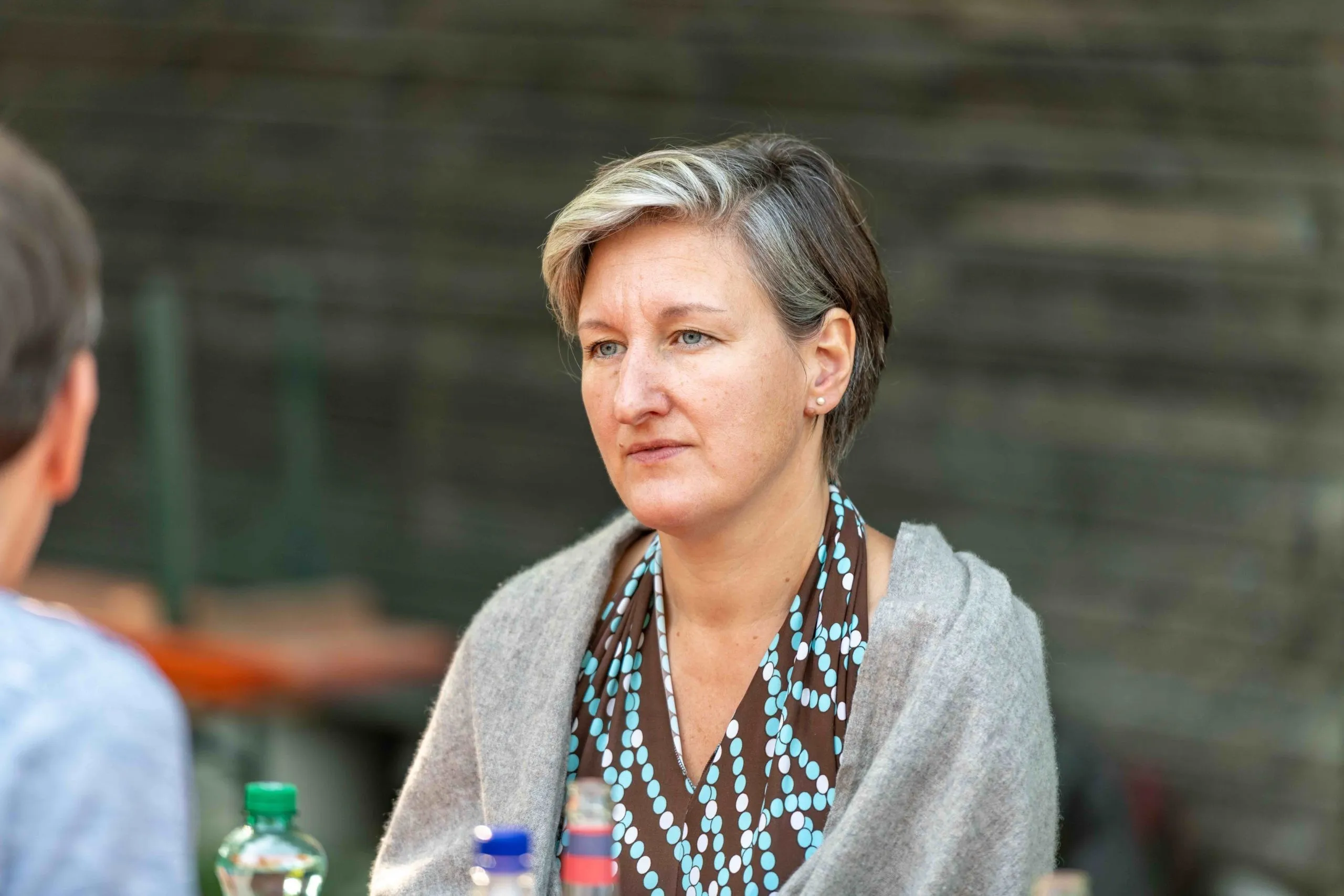 Ernst schauende Frau mit kurzen Haaren, gemustertem Oberteil und Jacke