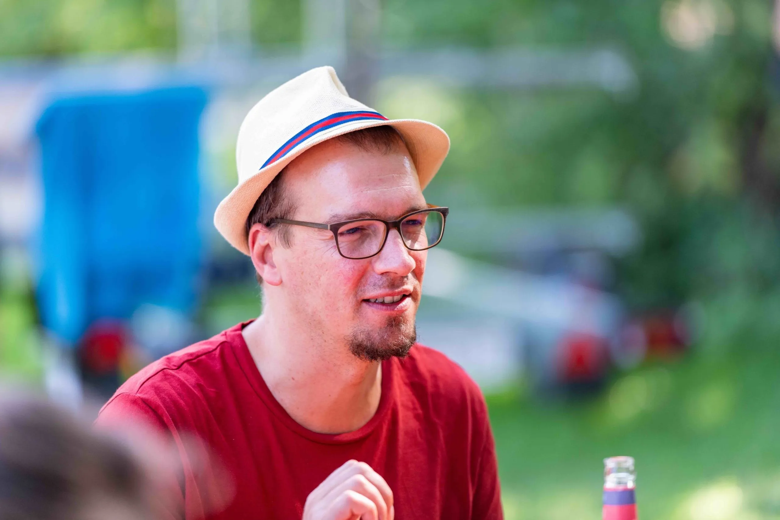 Mann mit Sonnenhut, Brille und rotem T-Shirt