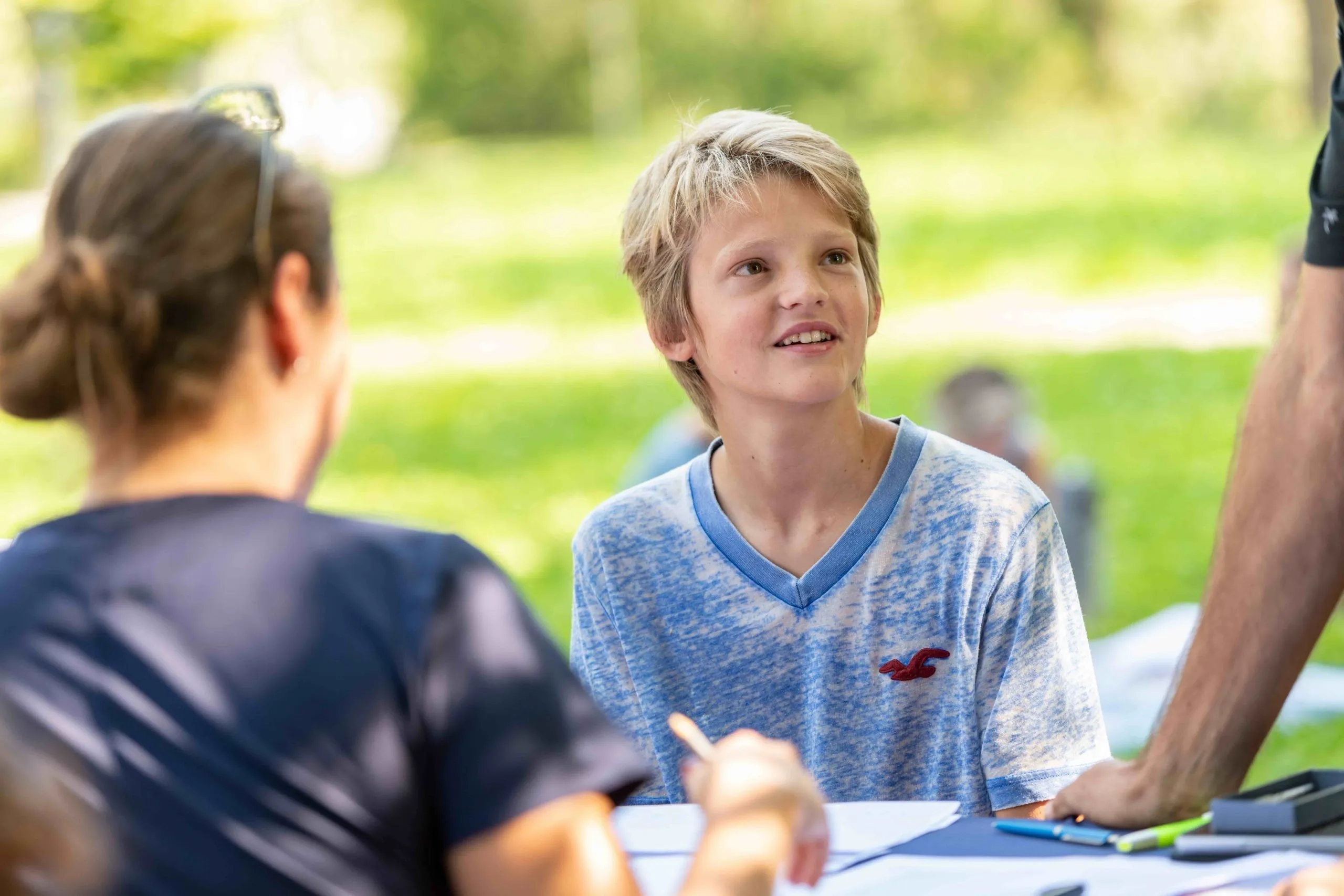 Blonder Junge sitzt lächelnd am Tisch