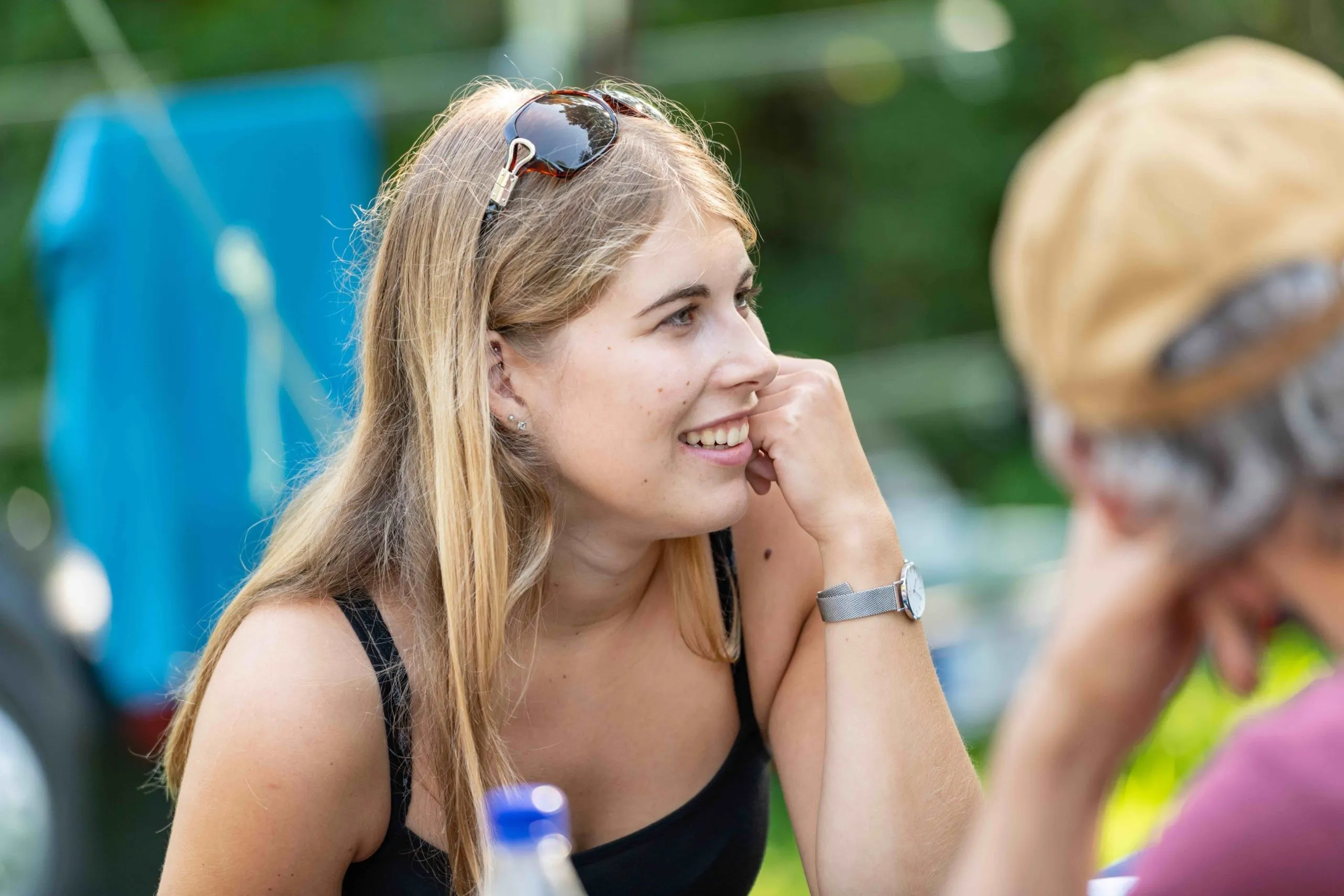 Lächelnde junge Frau mit Sonnenbrille im Haar und schwarzem Top