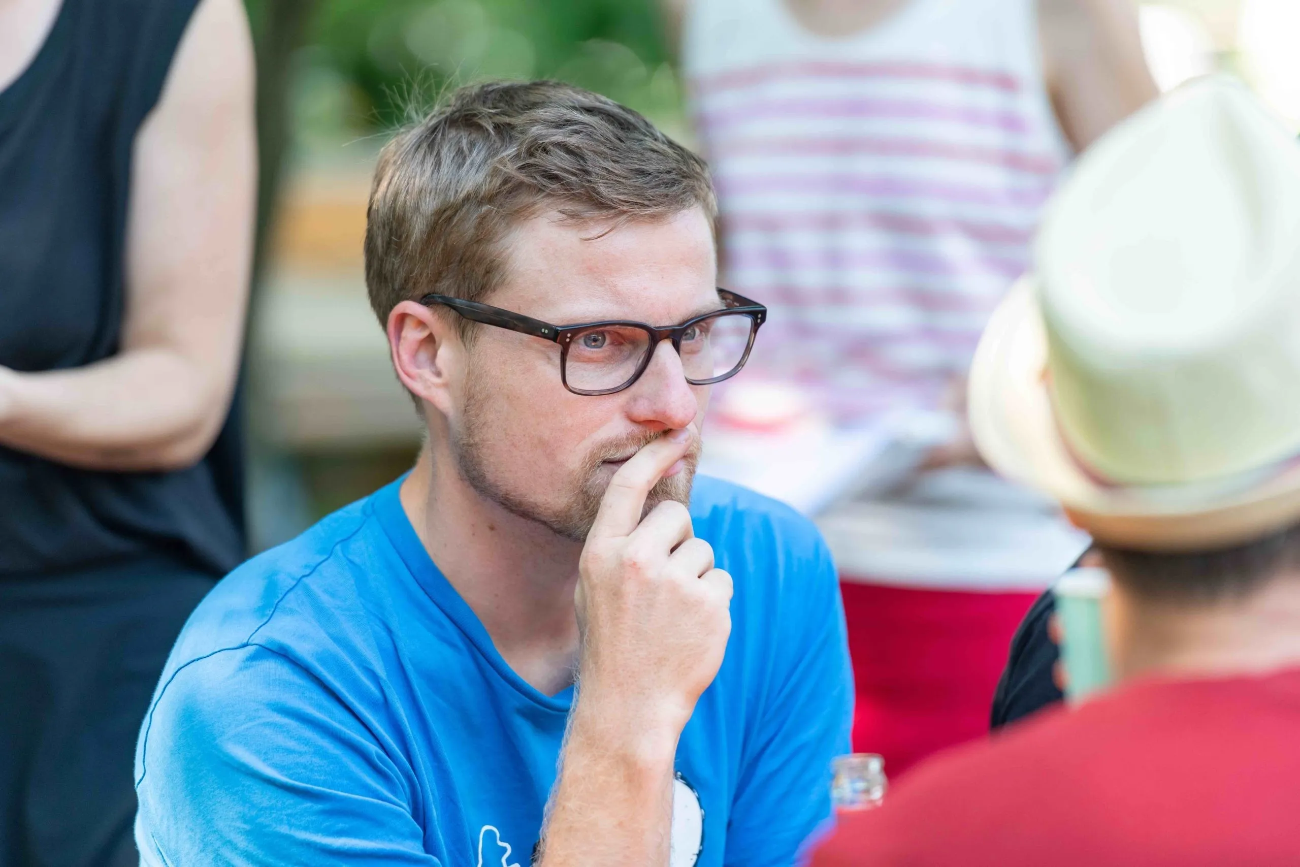 Nachdenklicher Mann mit schwarzer Brille und blauem T-Shirt