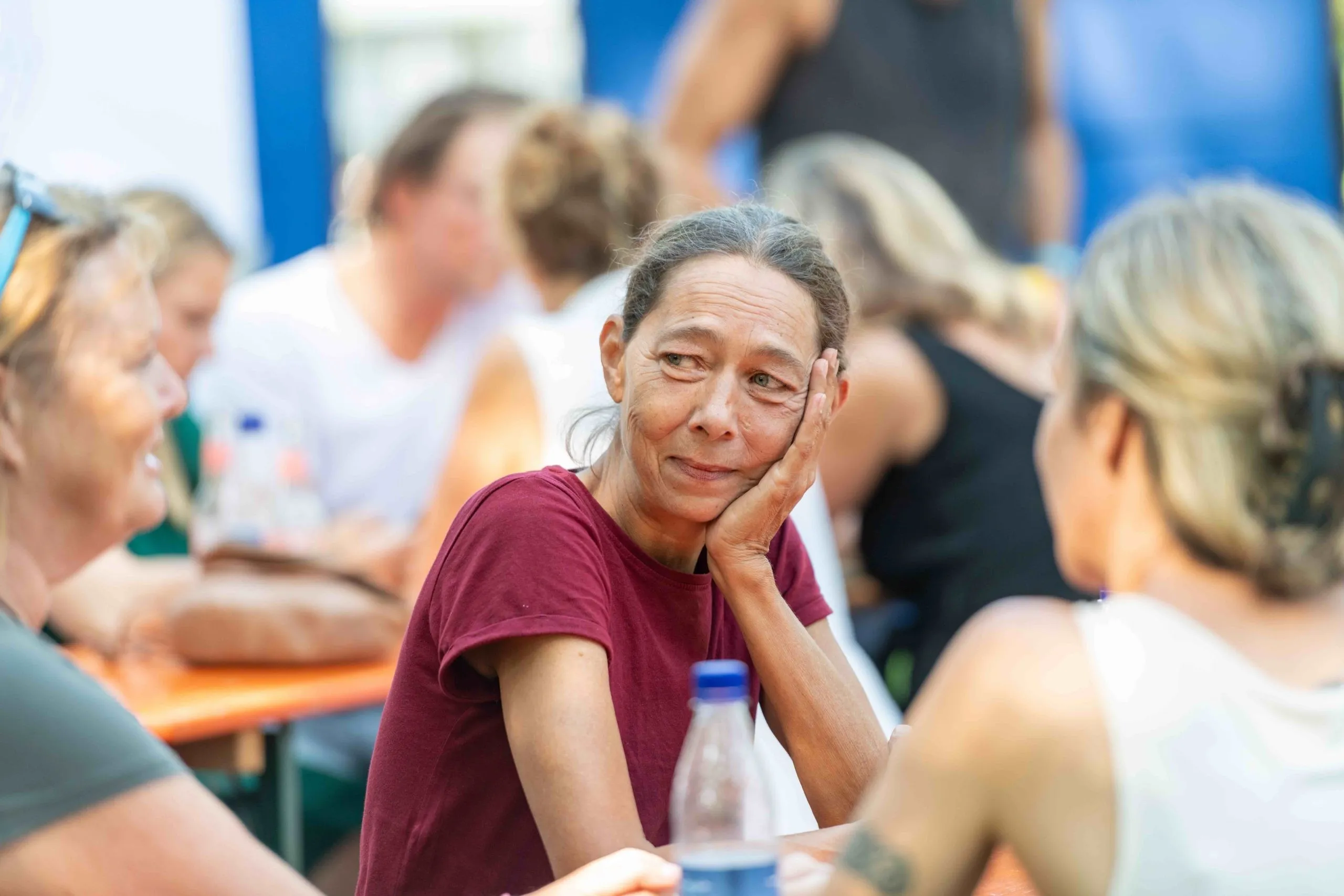 Ältere Frau mit rotem T-Shirt die sich den Kopf auf der Hand aufstützt