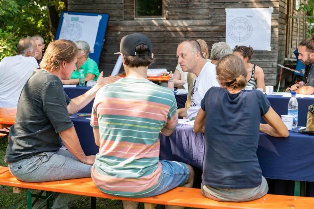 Vier diskutierende Menschen auf einer Bierbank sitzend