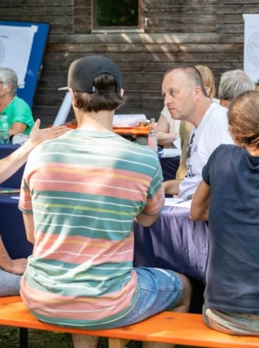 Vier diskutierende Menschen auf einer Bierbank sitzend