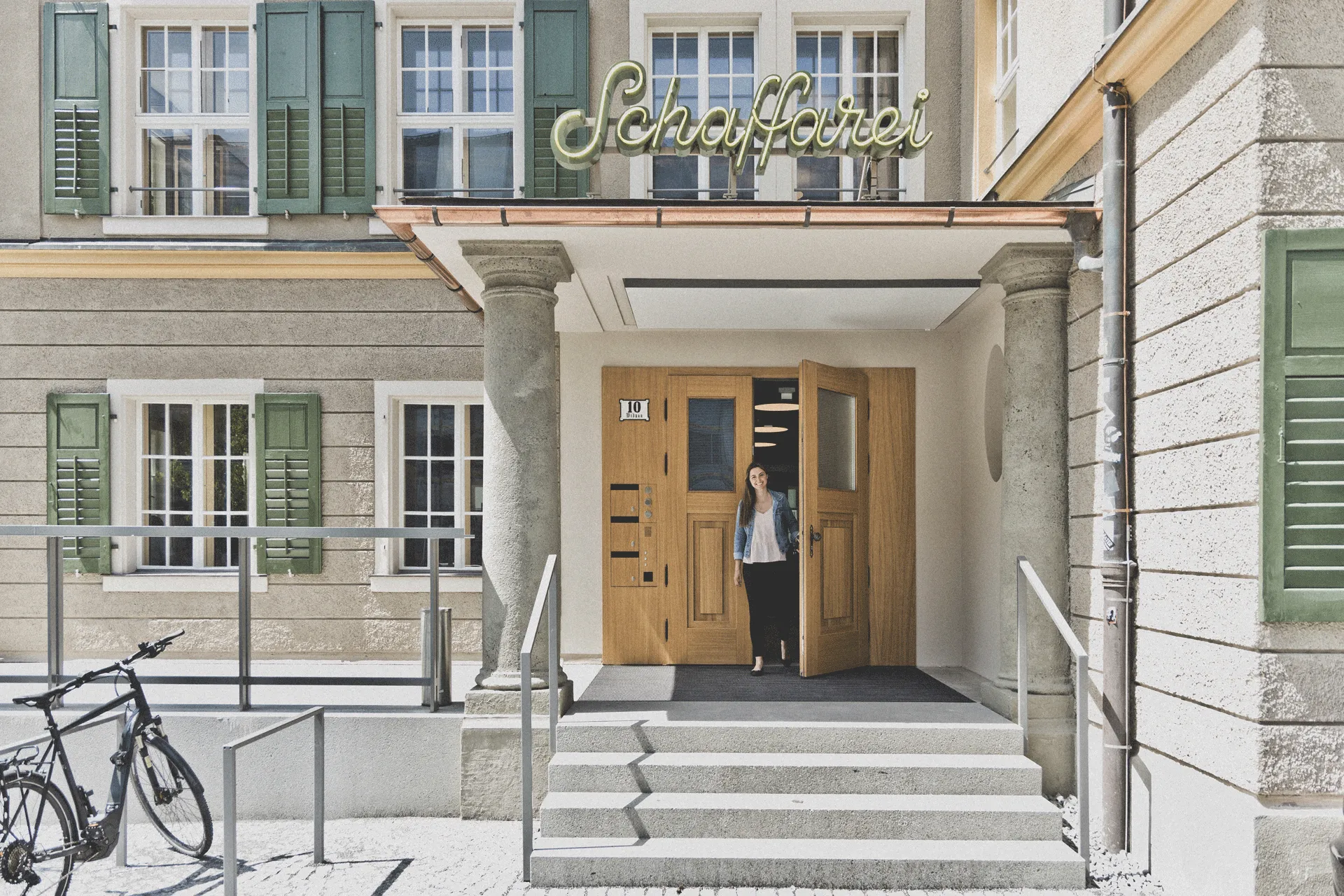 Geöffnete Haustüre des neuen Schaffarei Hauses mit Person