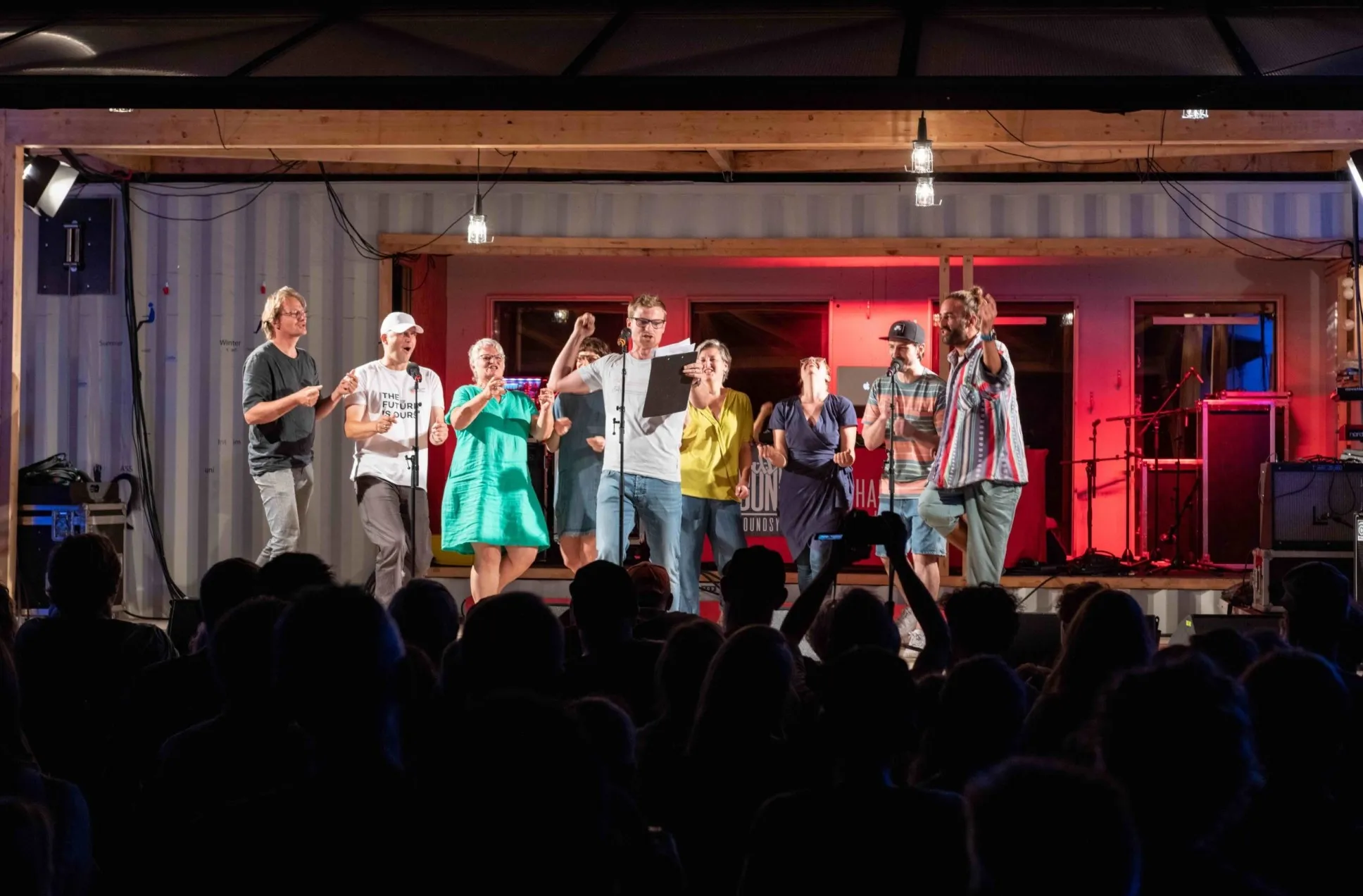 Menschen stehen auf einer Bühne und das Publikum ist zu sehen